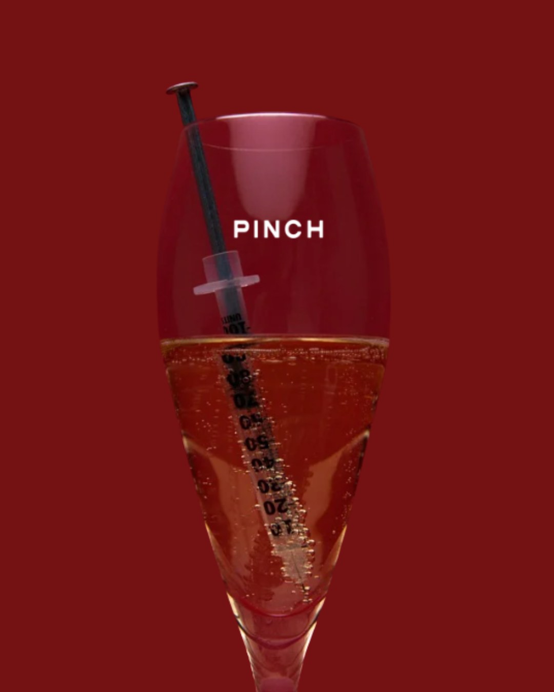 A PINCH-branded champagne glass with an aesthetic syringe, styled for a private gathering
